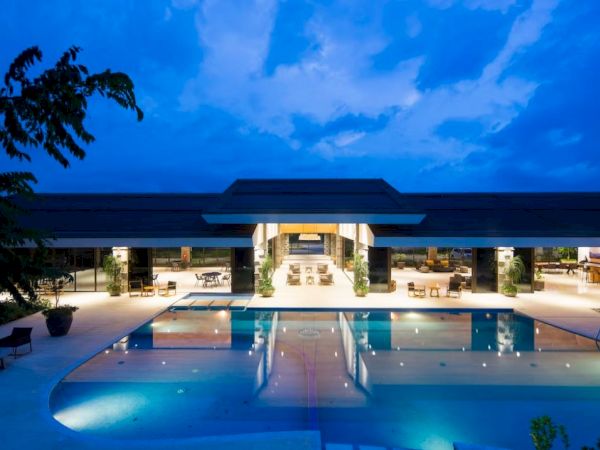A luxurious modern building with an illuminated pool in front and evening sky above, creating a tranquil and inviting atmosphere.