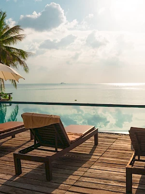 A serene beach scene with lounge chairs, umbrellas, and a calm sea in the background under a clear sky.