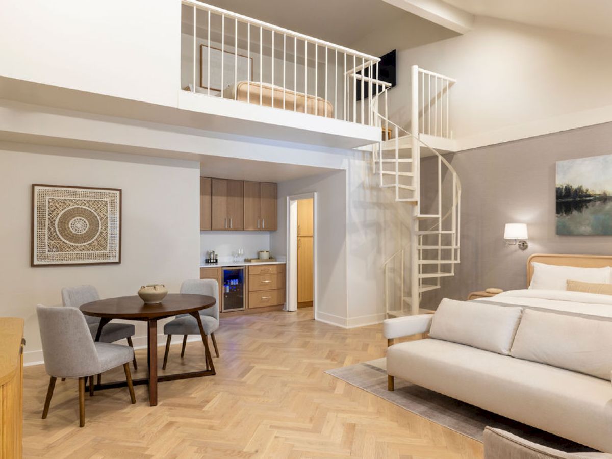 A modern loft apartment with a spiral staircase, kitchenette, dining area, and cozy seating space signals contemporary urban living.