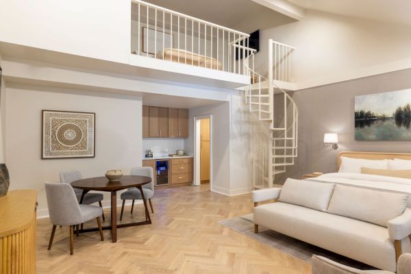 A modern loft with a spiral staircase, kitchen, dining area, and living space with a sofa and bed.