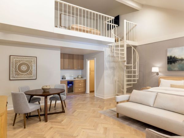 A modern loft with a spiral staircase, kitchen, dining area, and living space with a sofa and bed.