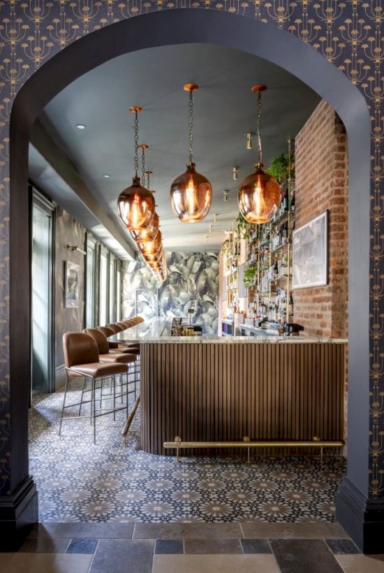 The image shows a stylish bar with pendant lights, a wooden counter, bar stools, and decorative tiles, viewed through an arched doorway.
