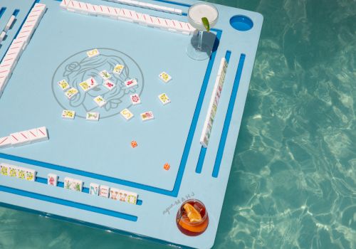 A Mahjong board with colorful matching tiles, two dice, and a drink on the side, ready for a game session.