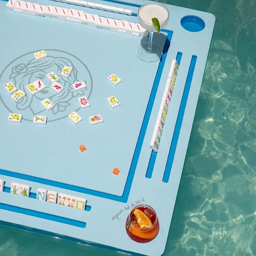 A Mahjong board with colorful matching tiles, two dice, and a drink on the side, ready for a game session.